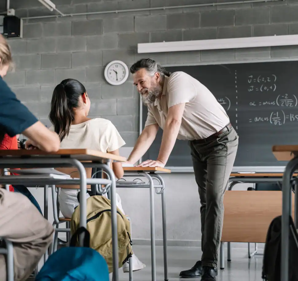 High-school teacher leaning in to engage a student during a math or science lesson, representing lived-experience counselling for secondary educators