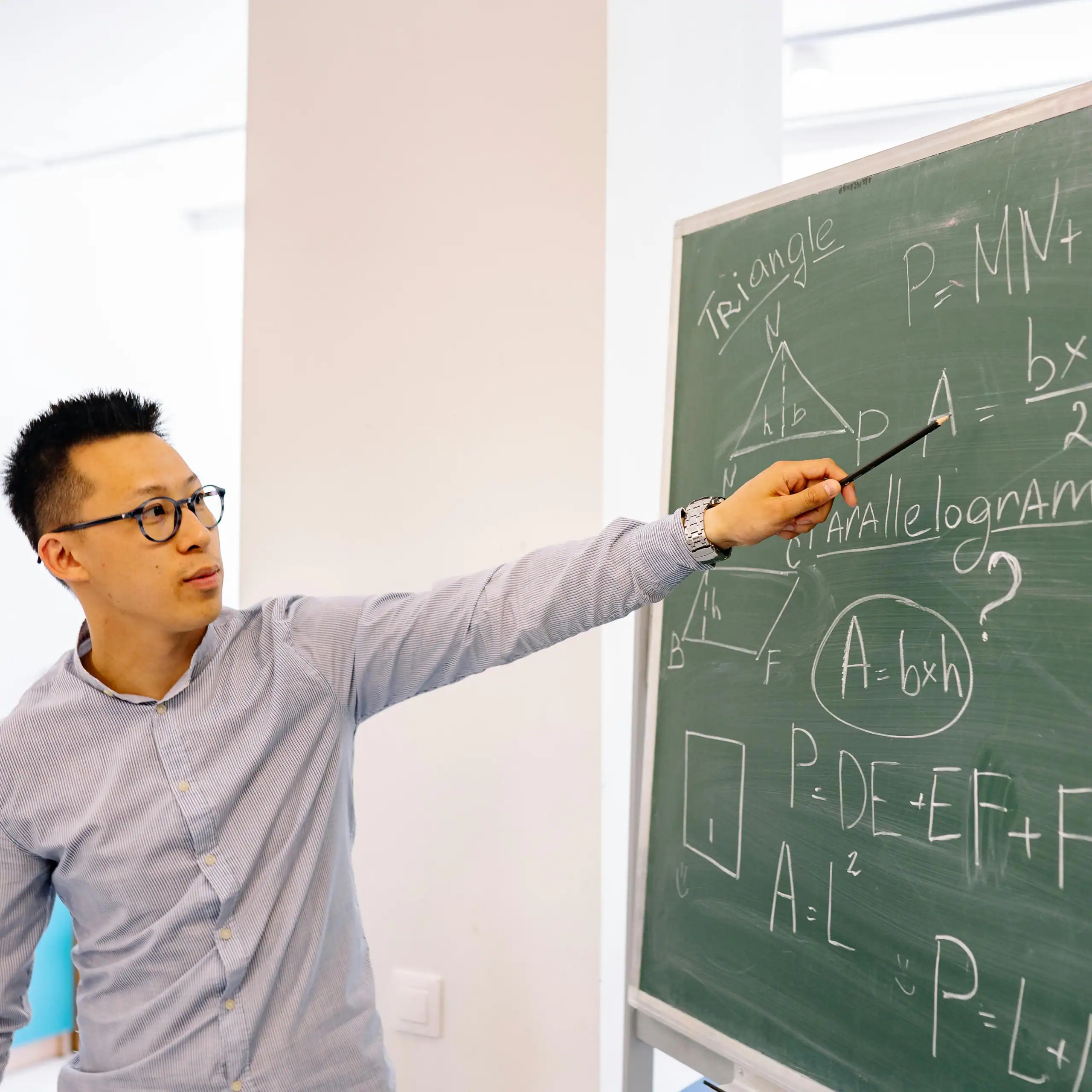 Teacher explaining a math lesson on a chalkboard representing focus, structure, and educator support through R.I.C.’s REACH Program
