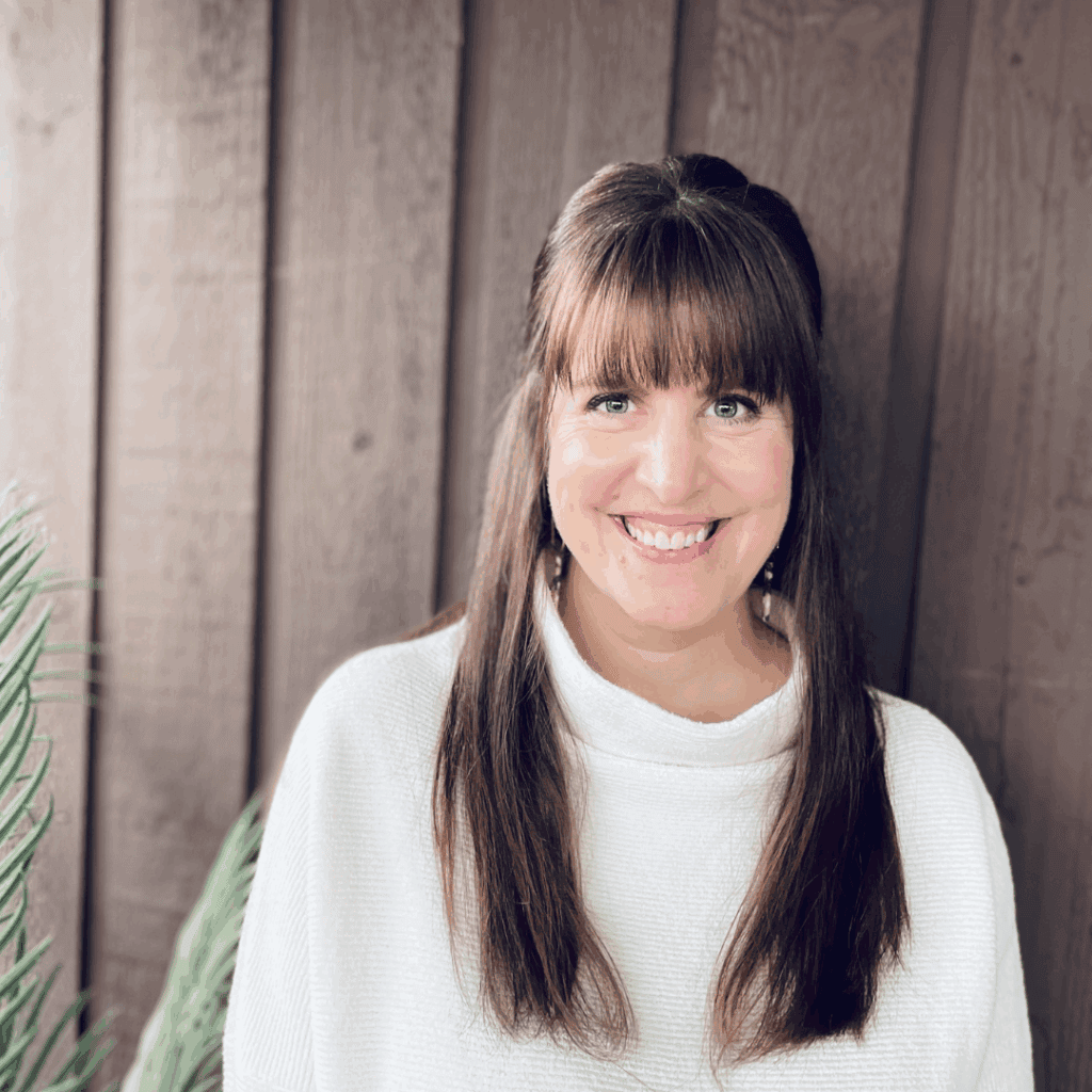 Professional portrait of counsellor Sharlene O’Reilley smiling outdoors in front of a wooden backdrop.