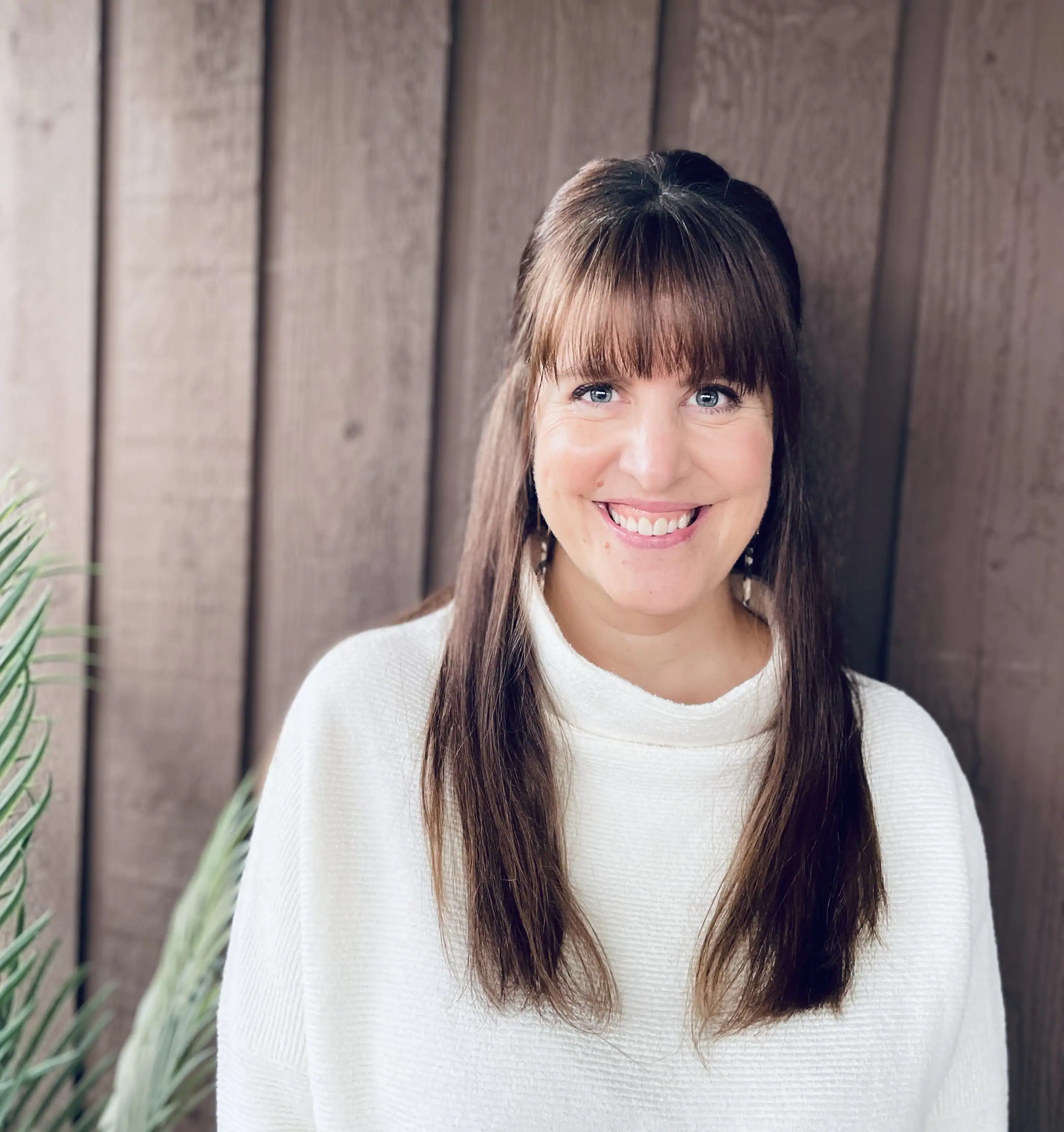 Professional portrait of counsellor Sharlene O’Reilley smiling outdoors in front of a wooden backdrop.