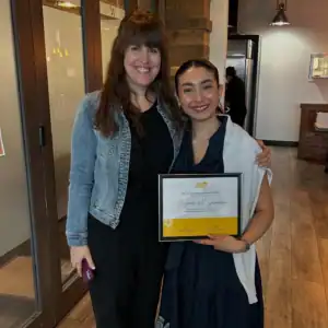 Yasmeen Al-Smarra holding her Graduate Student Internship certificate with her R.I.C. supervisor.
