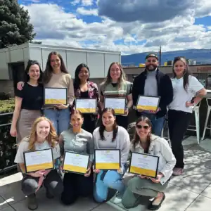 Group photo of the 2024 R.I.C. Master’s counselling intern cohort holding graduation certificates outdoors.